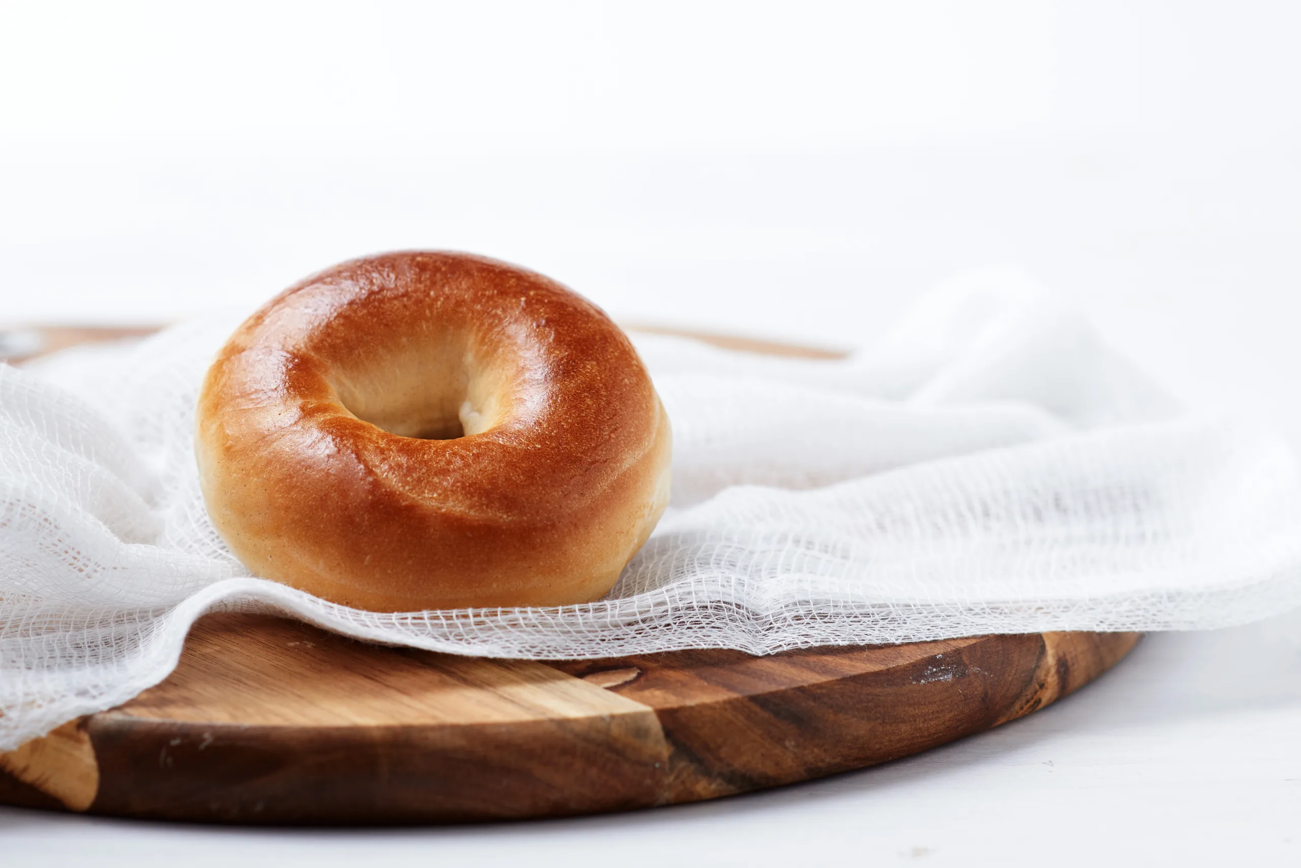 Vegan Bagel Vegan Plain Bagel Western Bagel Vegan Bagel Plain Vegan Bagel Plain Bagel on a white Towel on a Cork Board. Bagel with Hole in the Middle. Bagel no hole. Why do Bagels have Holes?